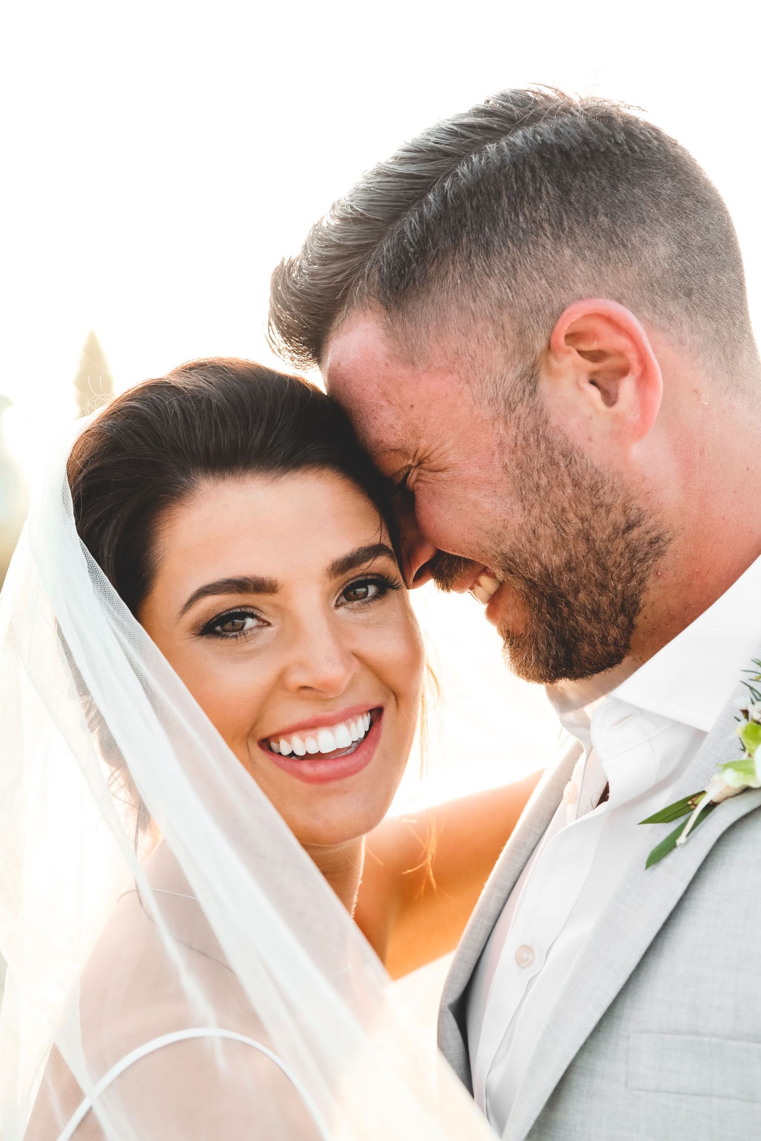 A tender moment between newlyweds on their wedding day against an ocean backdrop.
