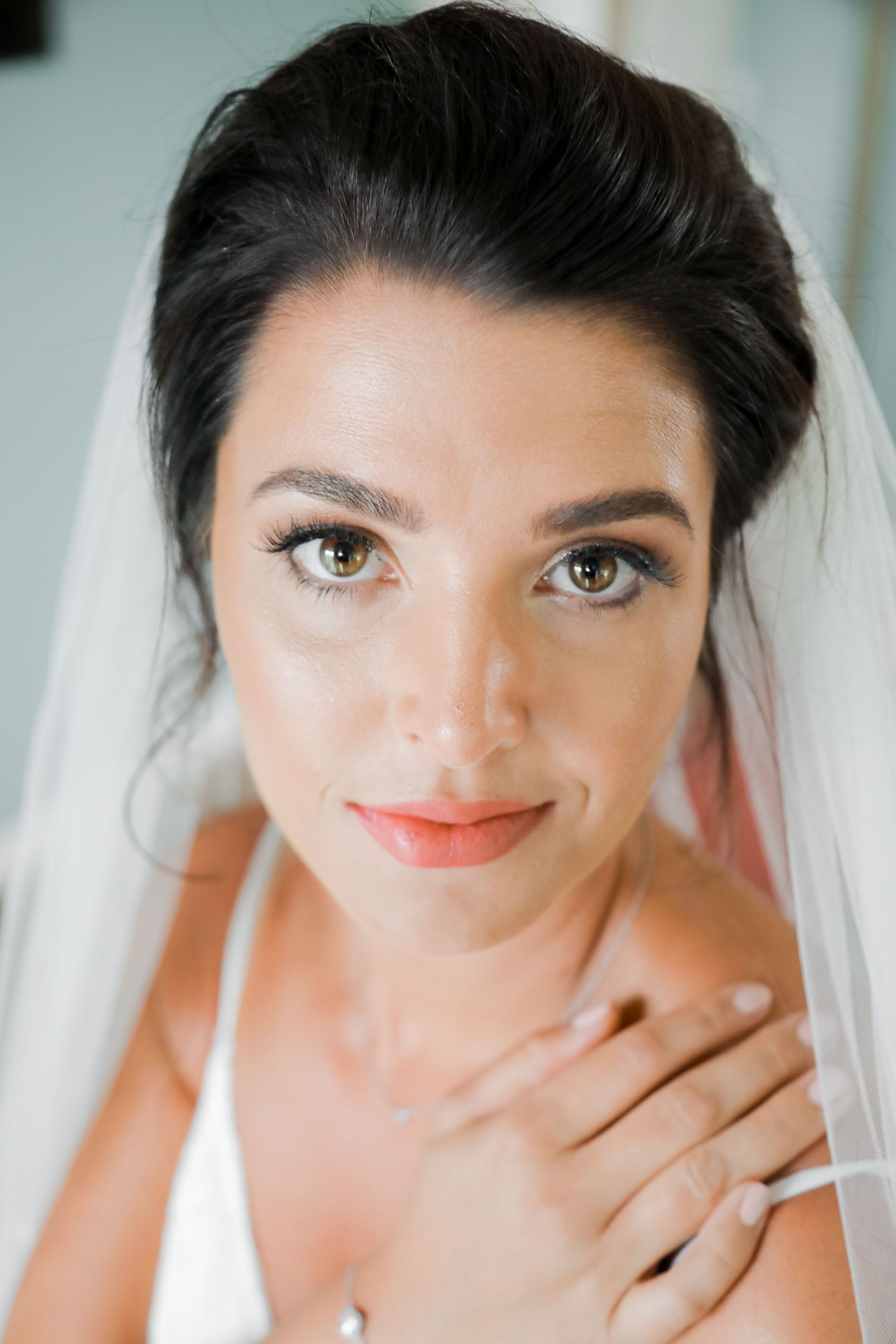Close up portrait of a bride wearing white veil and natural makeup.