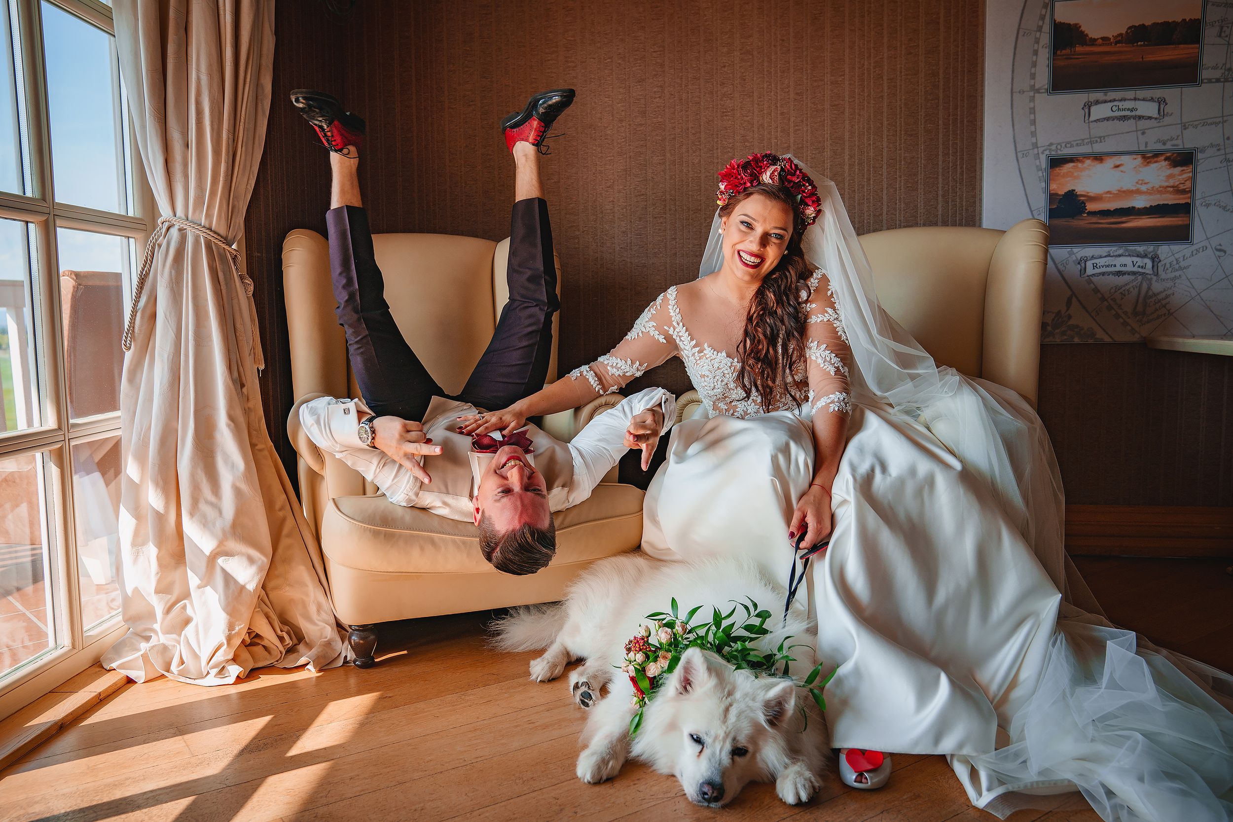 A playful wedding photo with upside down pose in a sunlit room with white dress and flowers.