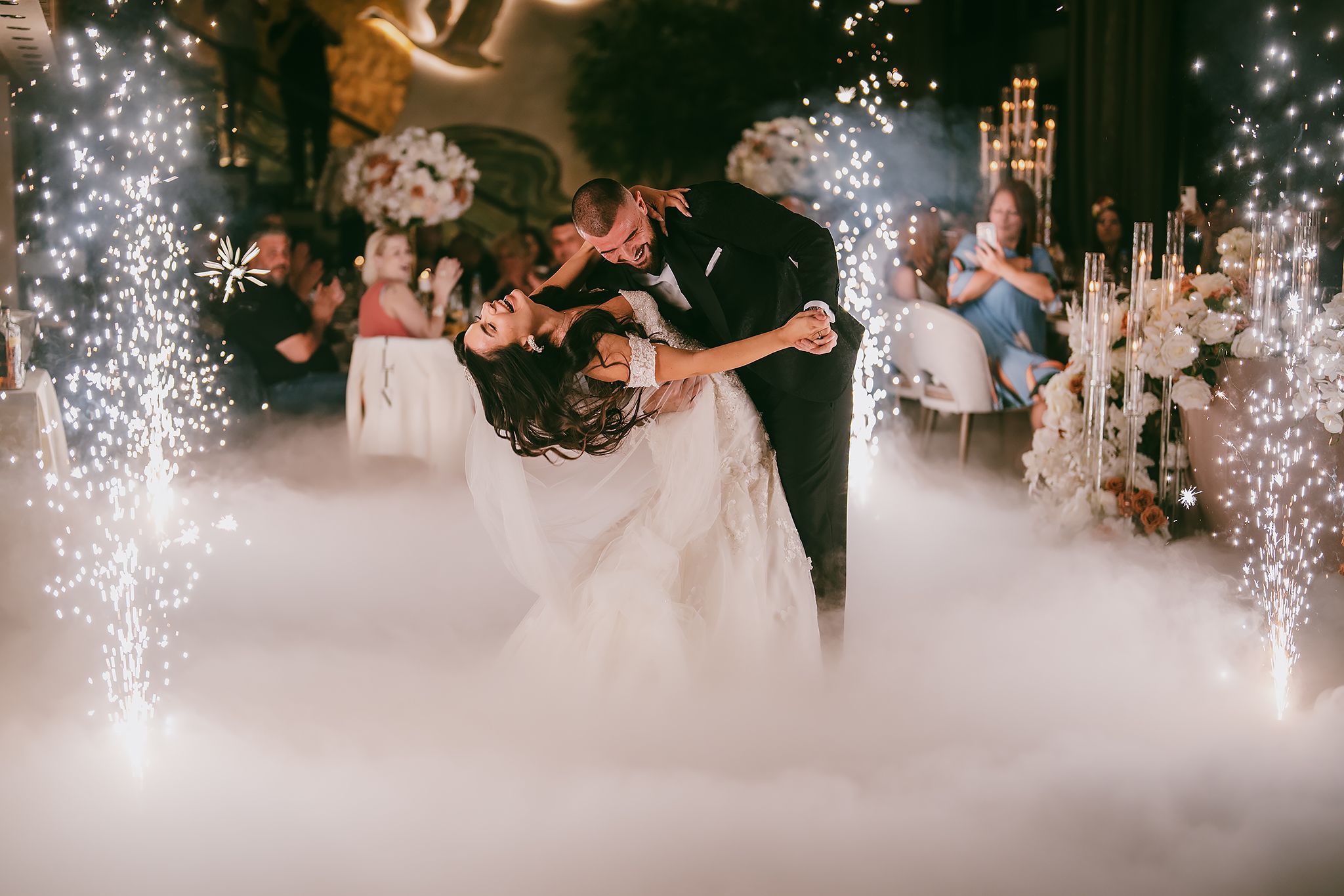 First dance with fog effects and sparklers creating a magical atmosphere at wedding reception.