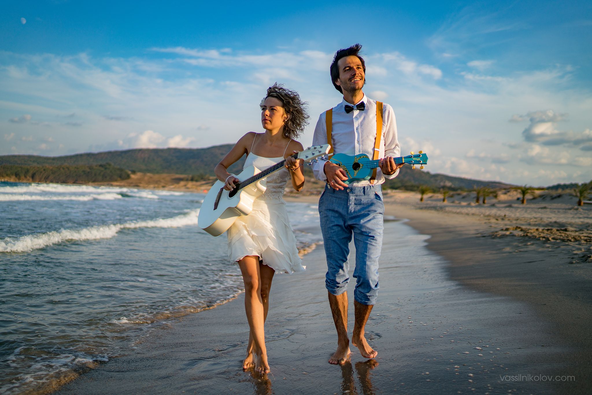 A carefree beach portrait with casual attire and guitar along the shoreline at sunset.