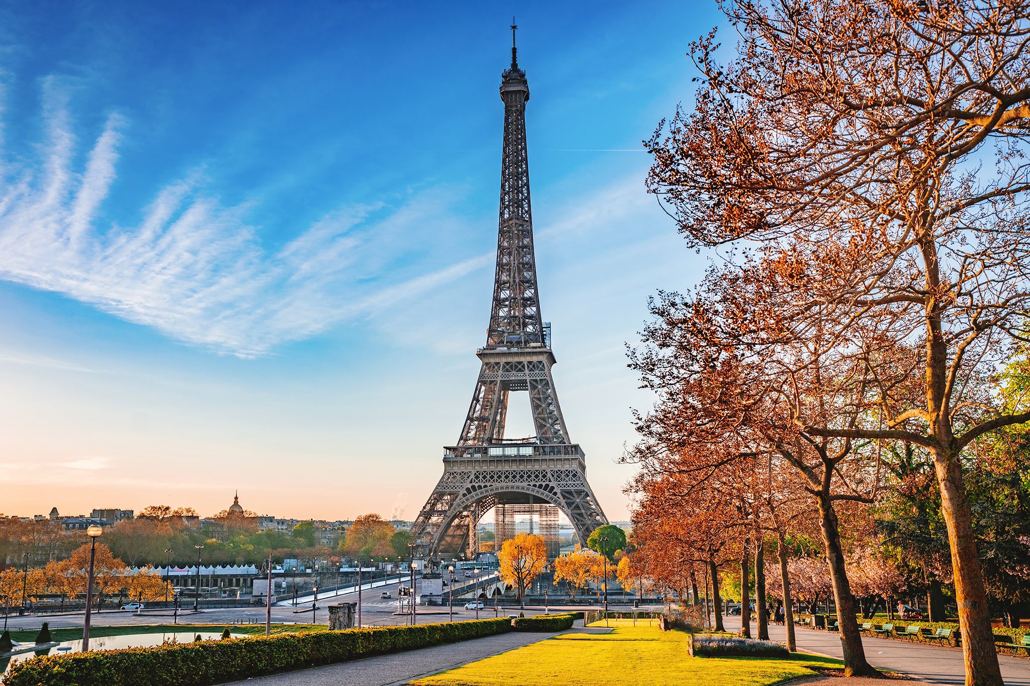 Eiffel Tower stands majestically against blue sky with autumn trees in Paris.