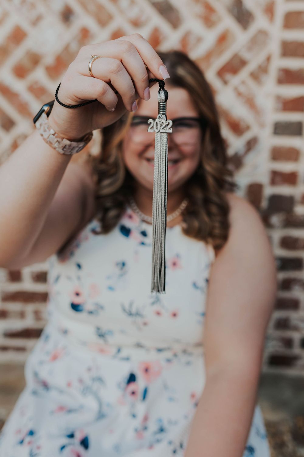 Close-up of hands holding graduation tassel with 2022 charm.