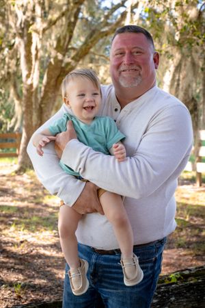 Joyful family moment captured outdoors among trees in natural lighting.