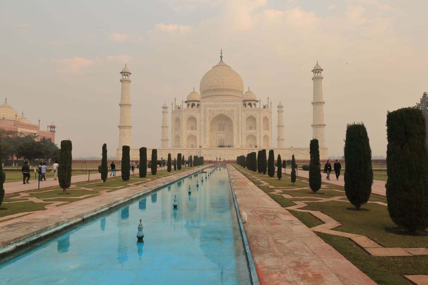 Iconic Taj Mahal with reflecting pool and manicured gardens at sunset in Agra, India.