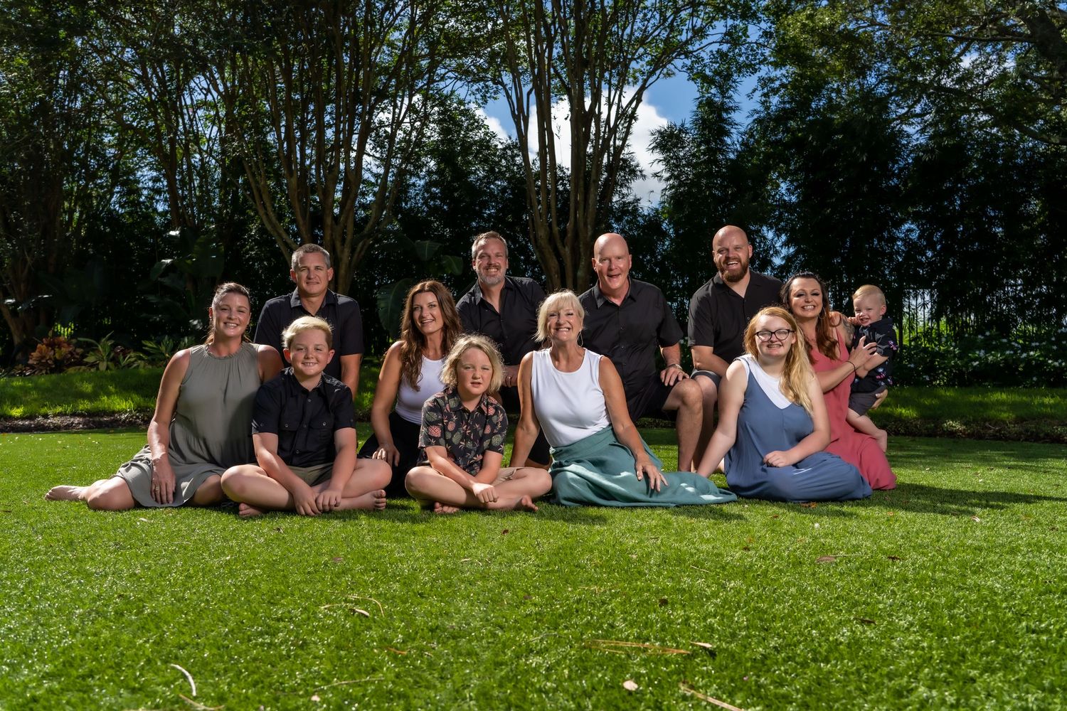 Group gathered together for casual outdoor photo on sunny grass lawn.