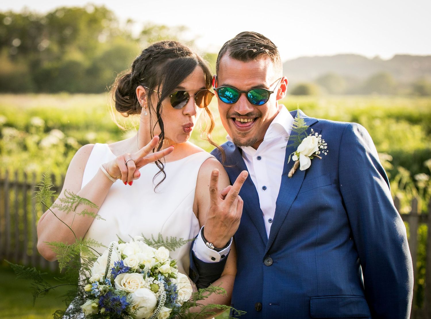 Wedding party poses outdoors in navy blue and white attire during golden hour.