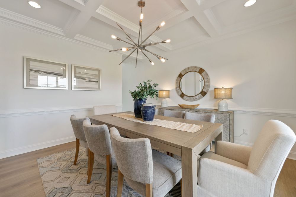 Real estate photography showcasing a modern, white dining room with a beautiful chandelier.
