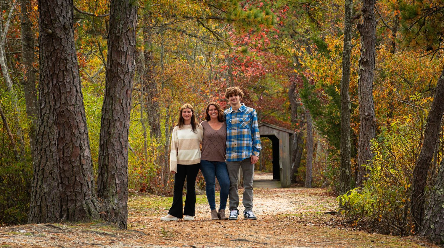 Three people standing together in middle of a trail in fall