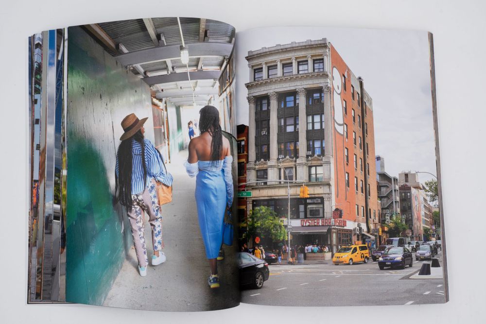 Open magazine spread showing an urban street scene with buildings and a yellow taxi in New York City.