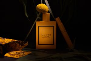 Golden Gucci perfume bottle photographed in low key lighting with vintage styling.