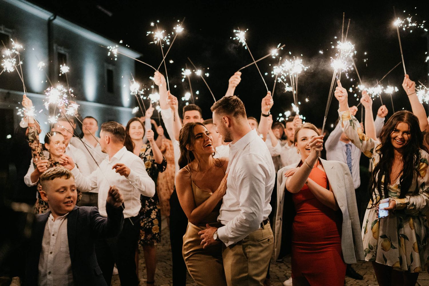 Party guests celebrate with sparklers during an indoor wedding reception.