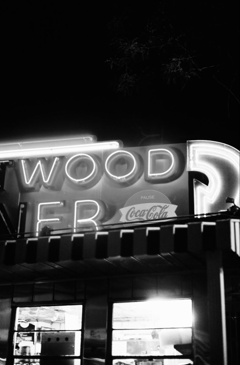 Illuminated neon storefront sign for Wood and Coca Cola at night.