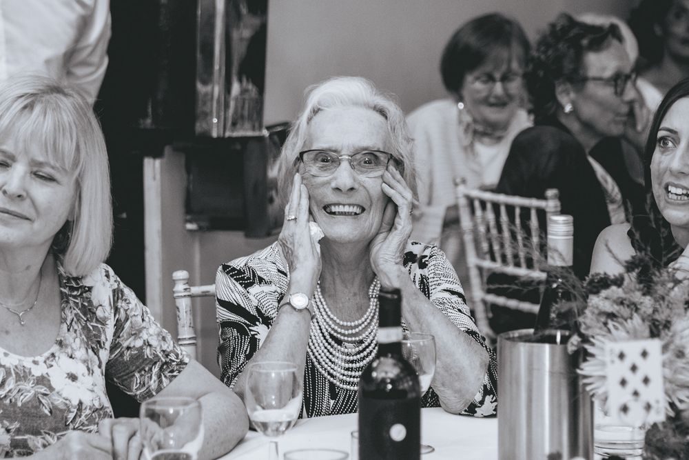 Guests laugh and smile during a joyful moment at an elegant dinner reception.