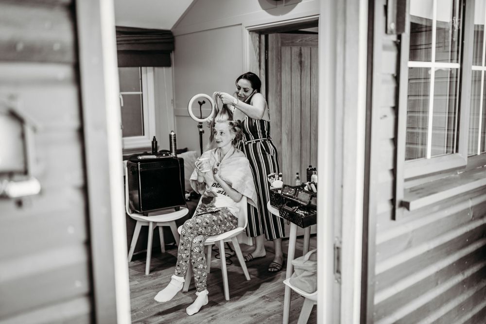 Black and white photo of a hairstyling session in a vintage interior setting.