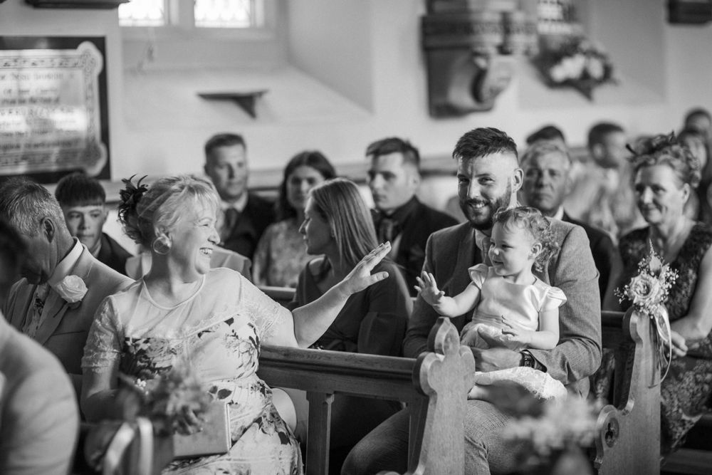 Black and white candid photo of wedding guests sharing laughter during the celebration.