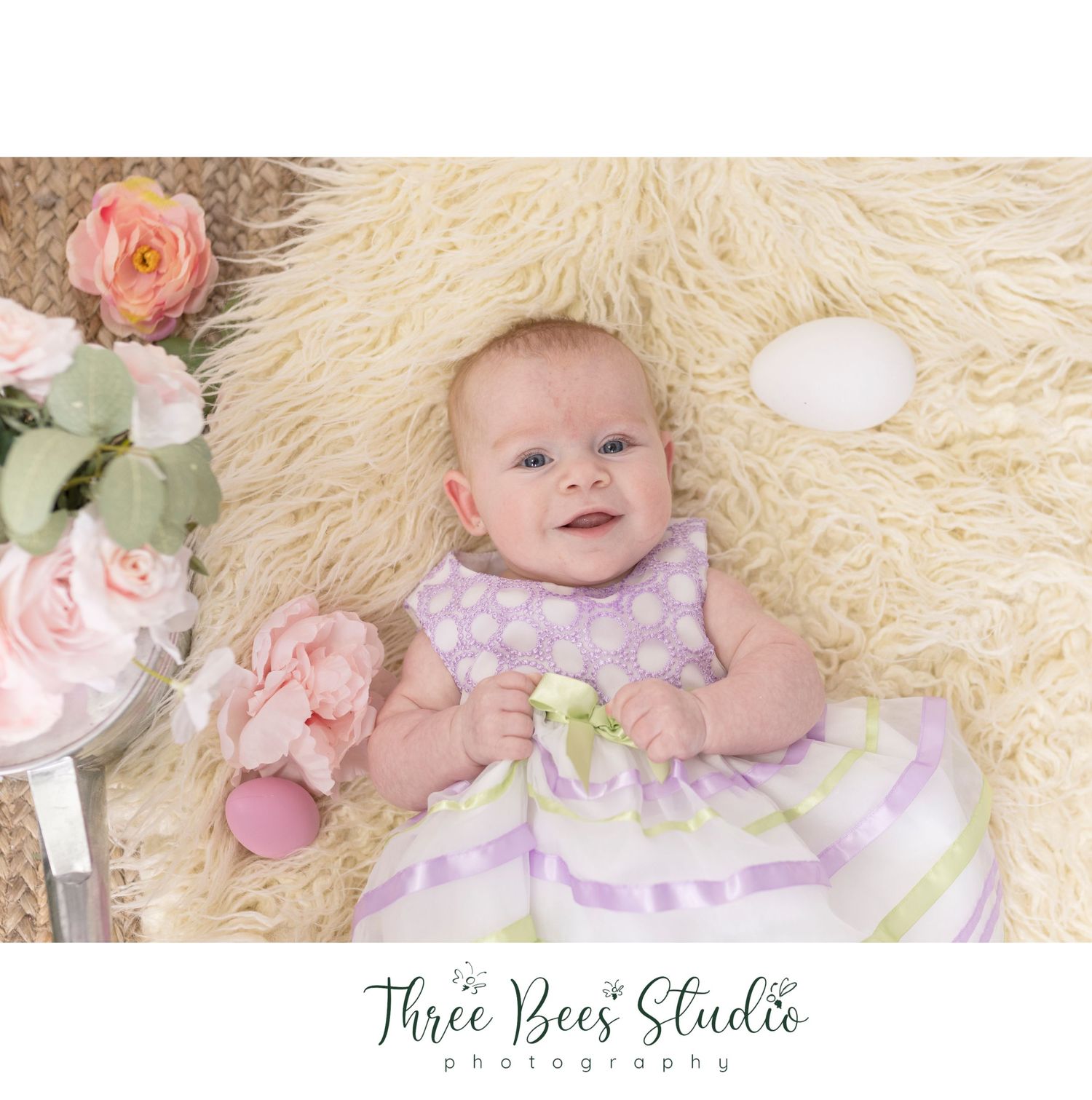 Sweet spring portrait featuring roses and cream-colored fur backdrop in soft pastel tones.