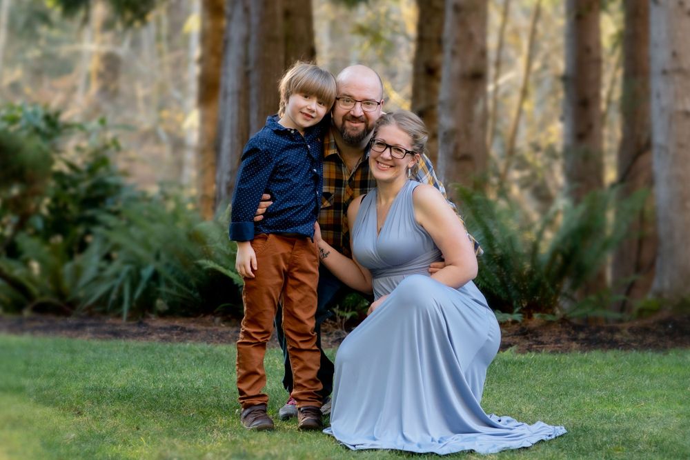 A family portrait in a wooded setting with lush greenery and natural lighting.