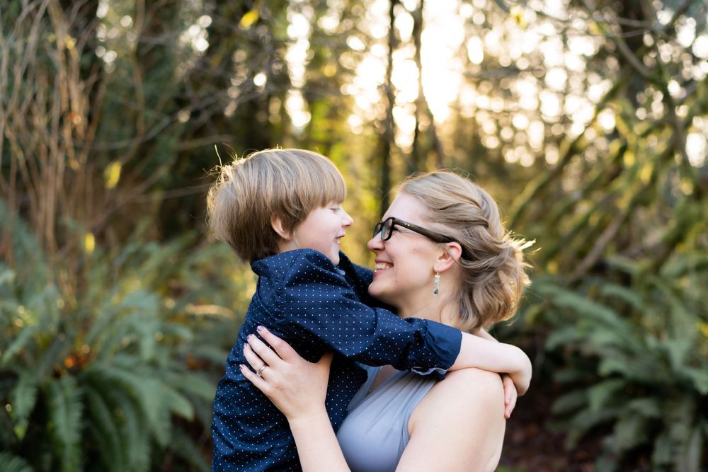 An intimate moment captured between parent and child in a sunlit forest setting.