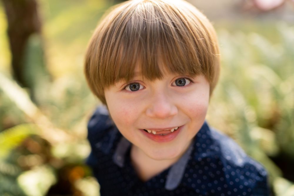 Close-up portrait shot against a soft natural background with bokeh effect.