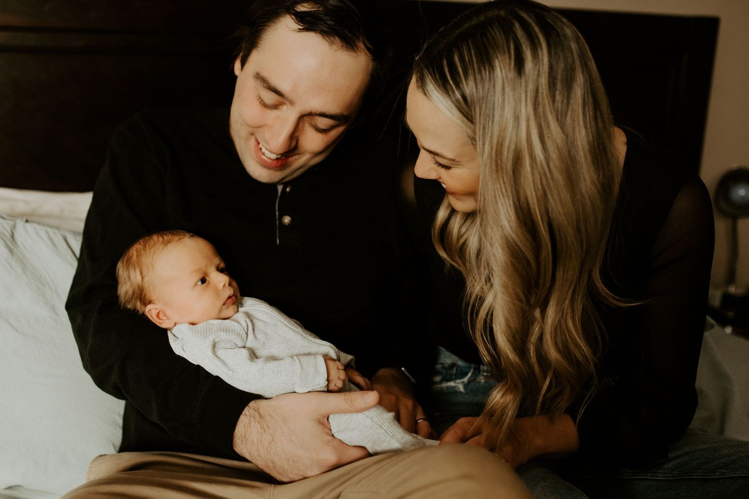Mom and dad hold their baby on the bed during their lifestyle newborn session.