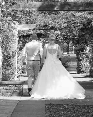 Black and white wedding photos showing couple walking through garden archway.