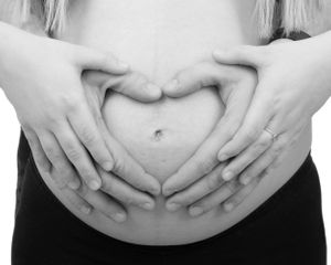 Black and white photo series showing hands cradling a pregnant belly in different poses.