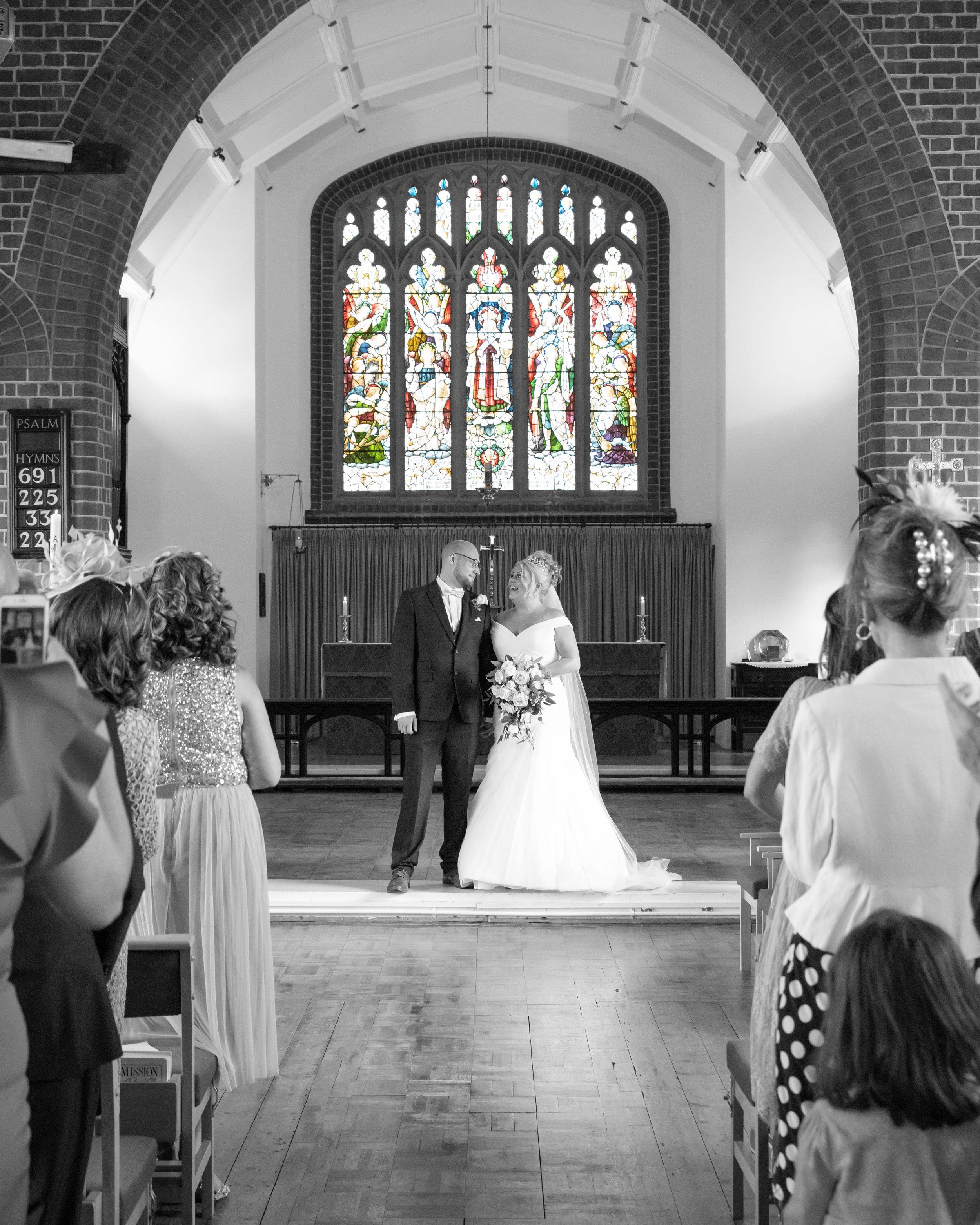 A sequence of black and white wedding ceremony photos showing a church interior with stained glass windows and arches.