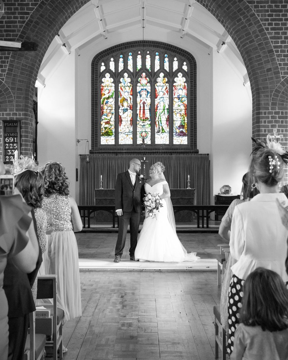 A sequence of black and white wedding ceremony photos showing a church interior with stained glass windows and arches.