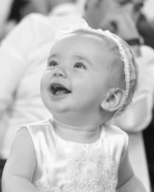 Black and white portrait series of baby in white lace dress looking up with joyful expressions.