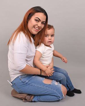 Mother and child in matching white shirts and jeans sitting together during photo session.