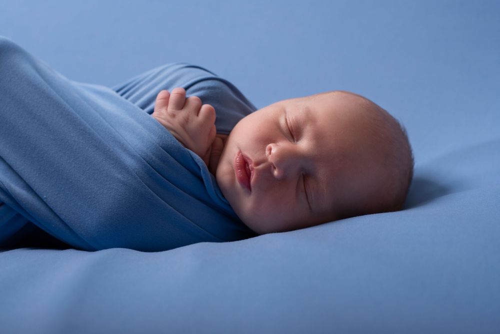 A sleeping infant wrapped in blue blankets.