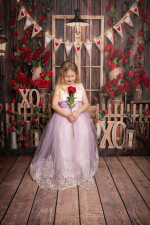 Valentine's themed photo shoot with lavender dress against rustic wooden backdrop with heart bunting.