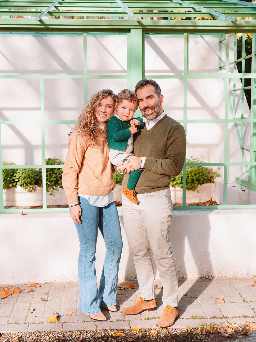 Family portrait session against a white greenhouse structure with green trim.