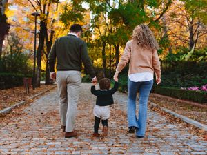 Family walking together on a leaf-covered path during autumn.