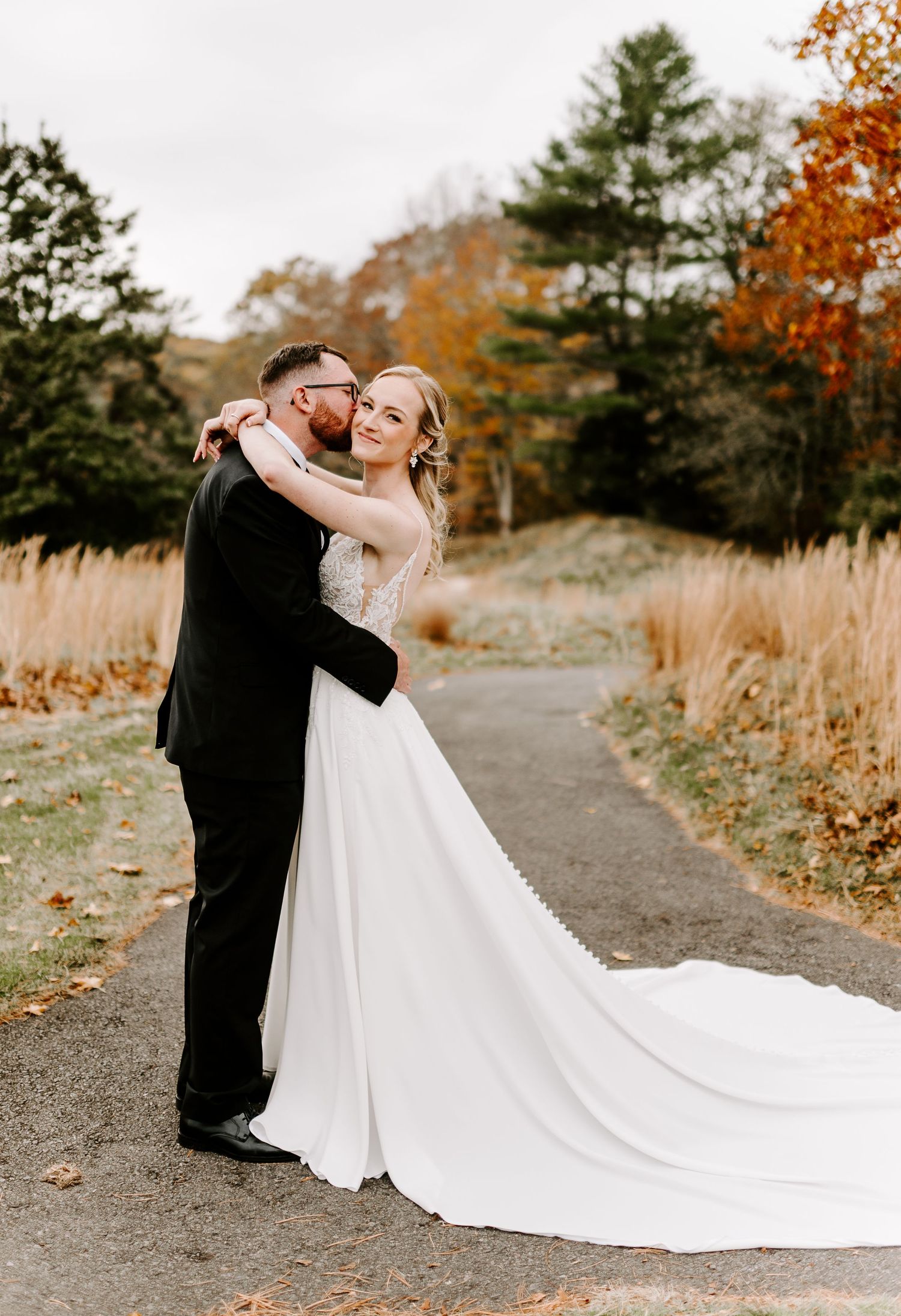 Couple dancing together on rustic path with bride's dress trailing behind.