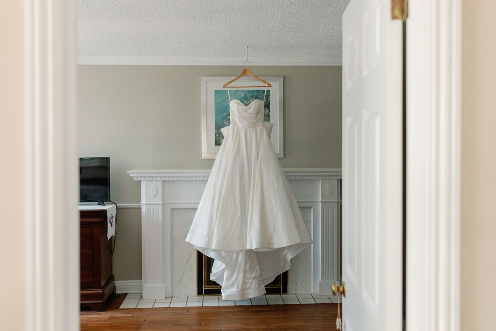 White wedding dress hanging in a bright room with mint green accents.
