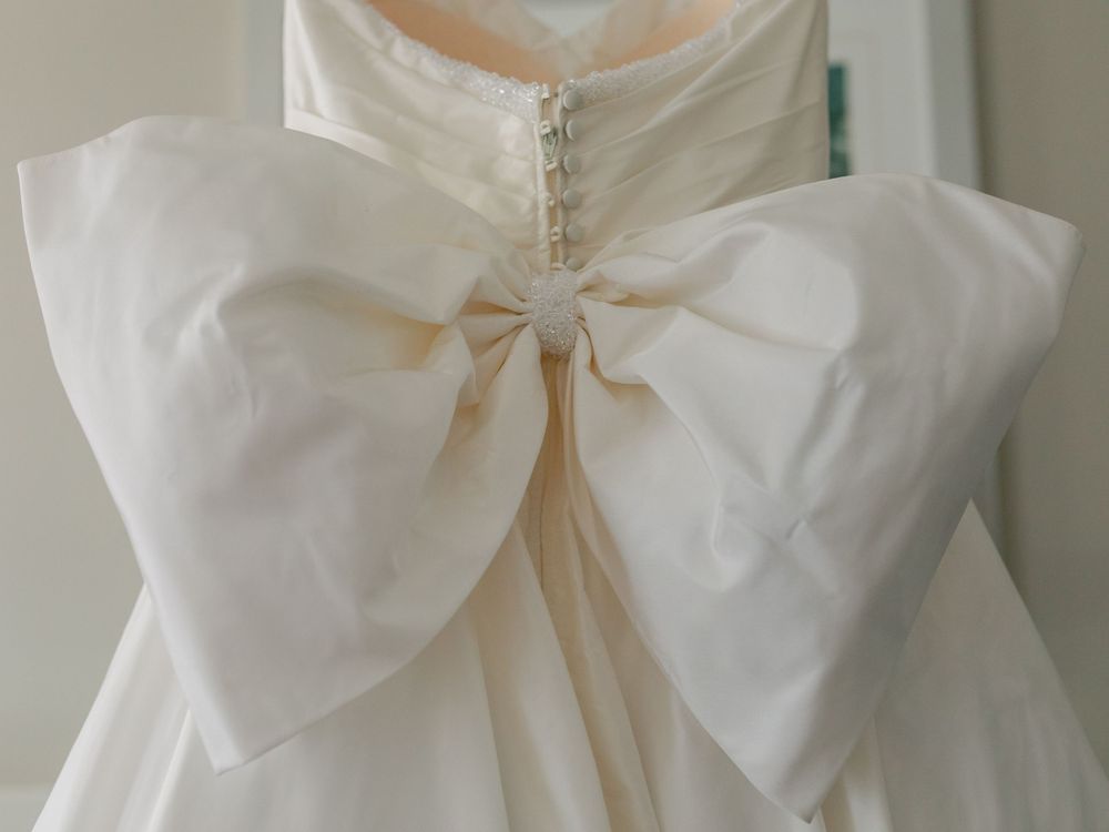 Detailed view of a large white bow on the back of a wedding dress.