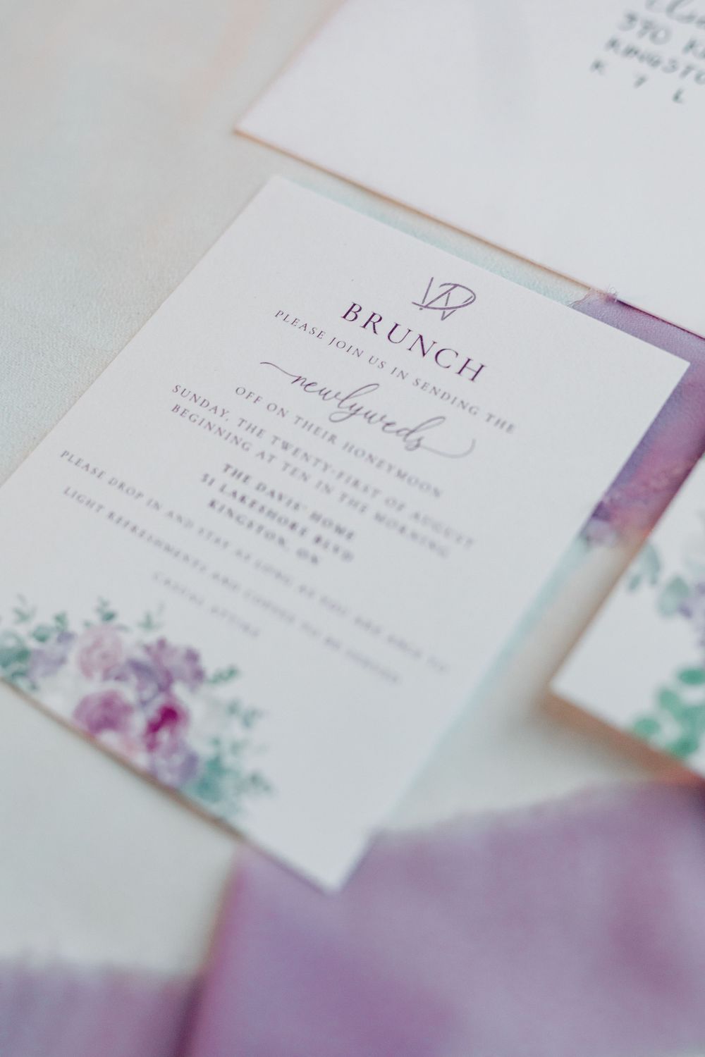Close-up details of wedding invitation text with purple watercolor accents.