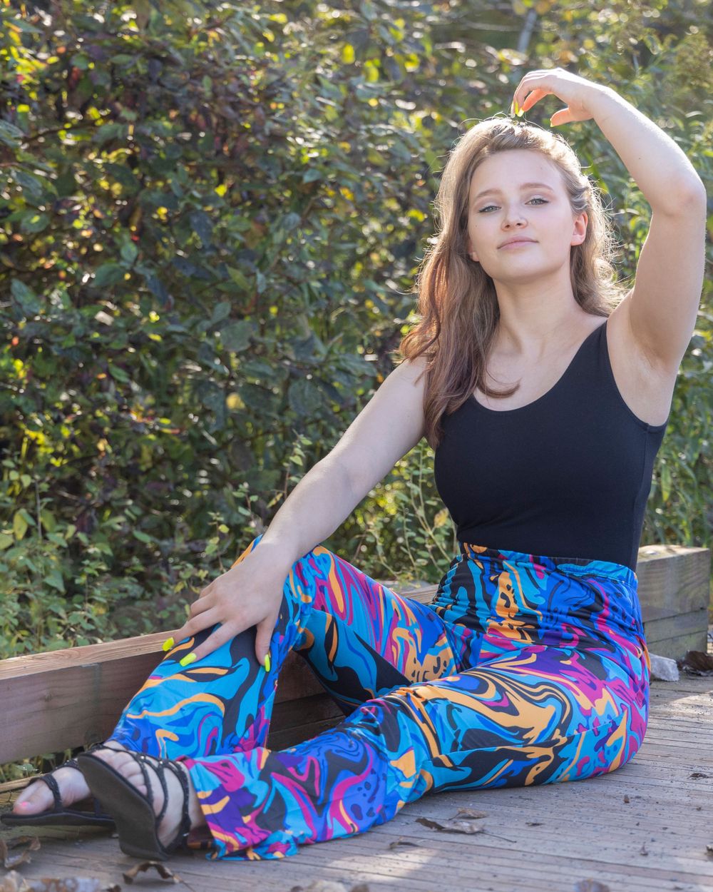 Figure in colorful patterned pants relaxing on wooden deck outdoors.