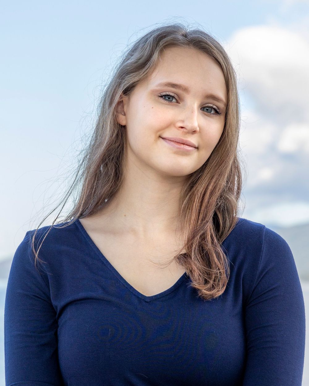 Portrait against blue sky with white clouds in natural lighting.