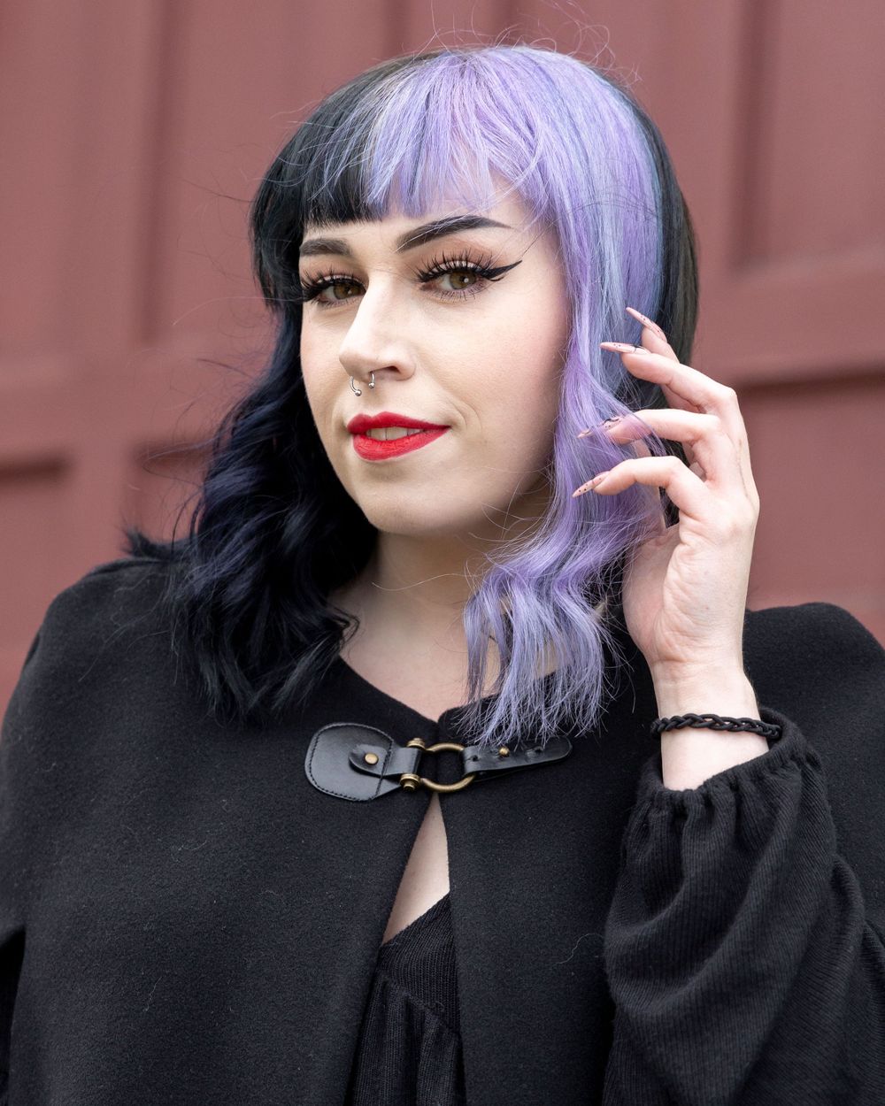 Gothic style portrait with purple-black hair, red lipstick, and black cape against burgundy background.