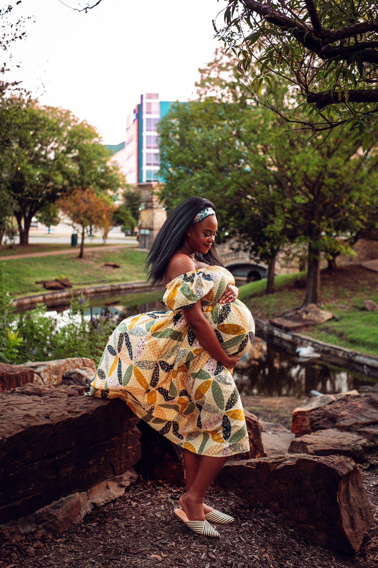 Person in patterned dress poses dramatically on outdoor rock formation.