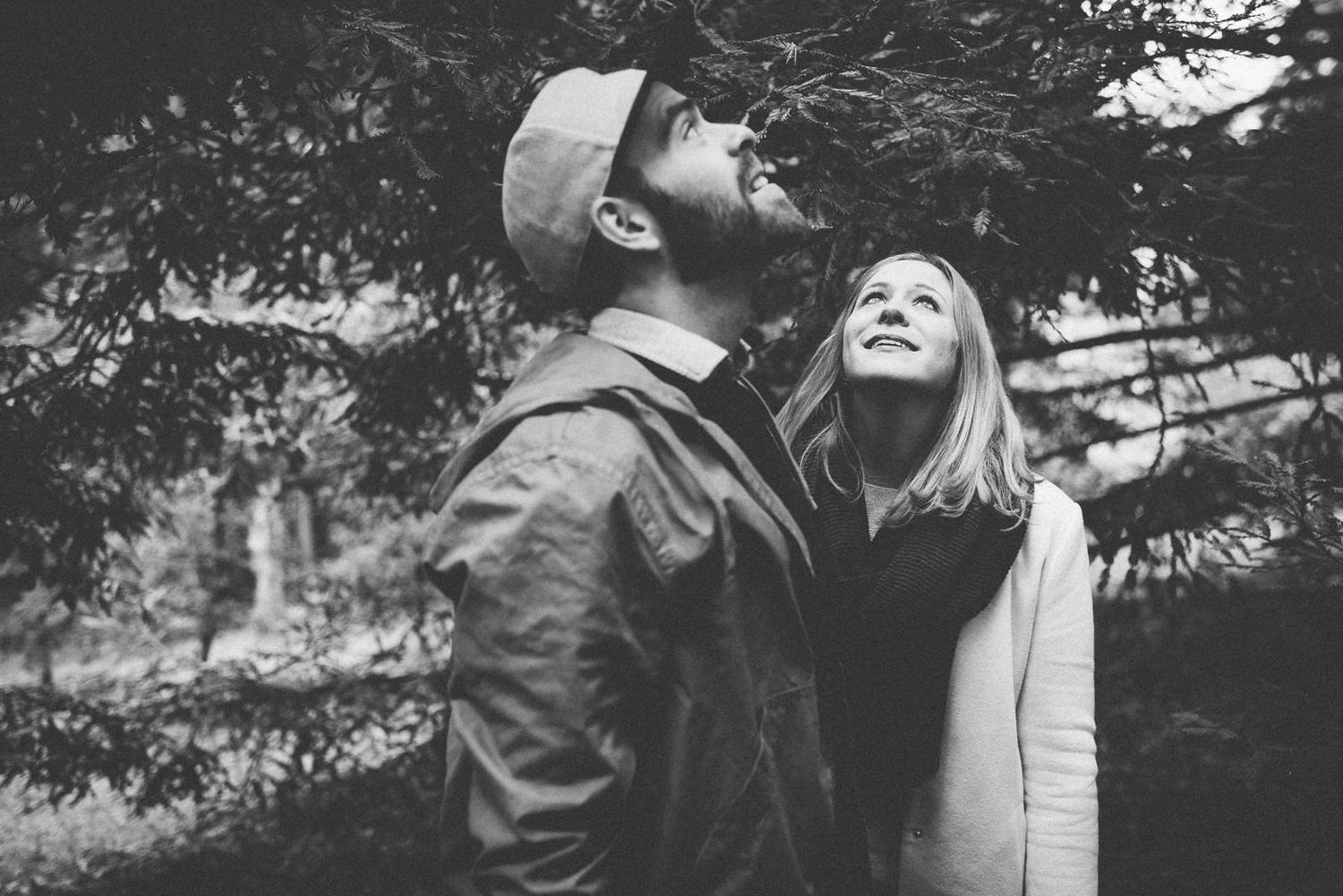 Couple looking upward together in dramatic black and white forest scene.