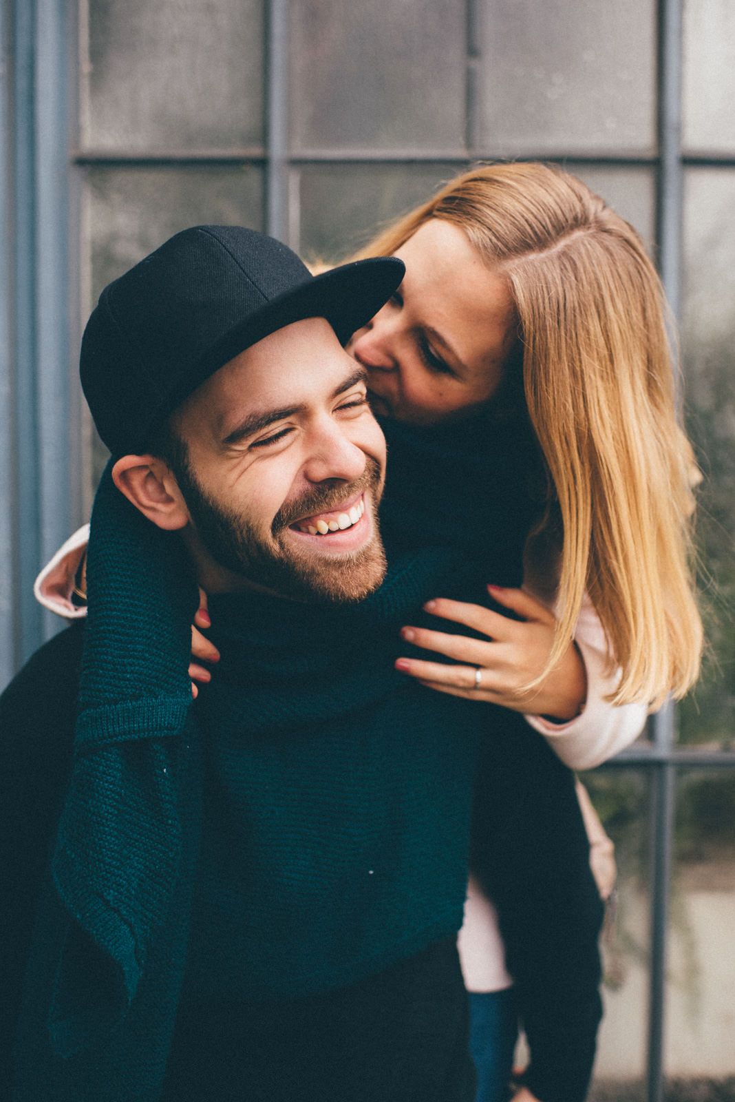 A tender moment shared between a couple against an industrial-style window backdrop.