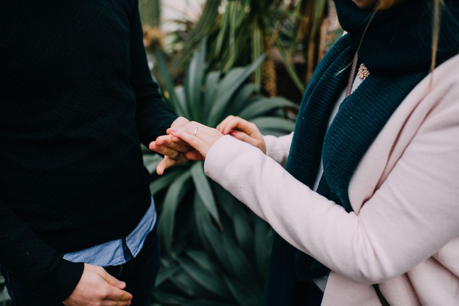 Close-up of hands exchanging rings during intimate moment.