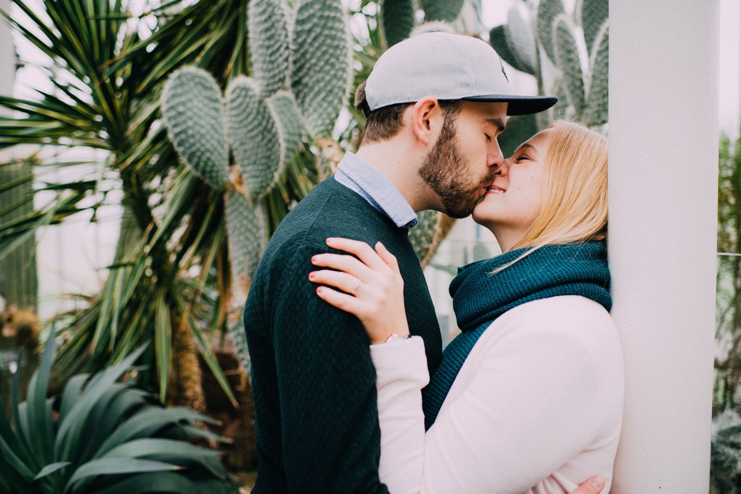 Intimate moment between couple in front of tropical plants and cacti.