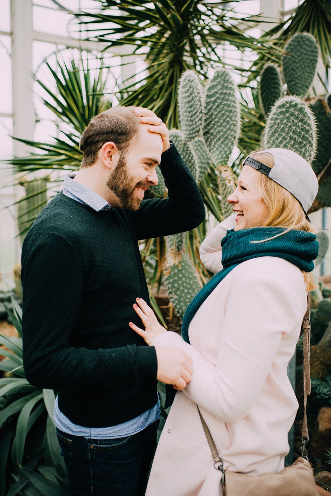 Joyful interaction between couple surrounded by indoor greenhouse plants.