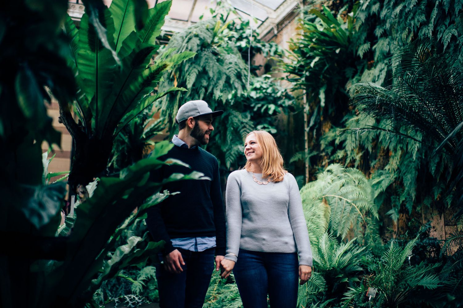 Couple sharing a moment together surrounded by tropical plants and greenery in a greenhouse.