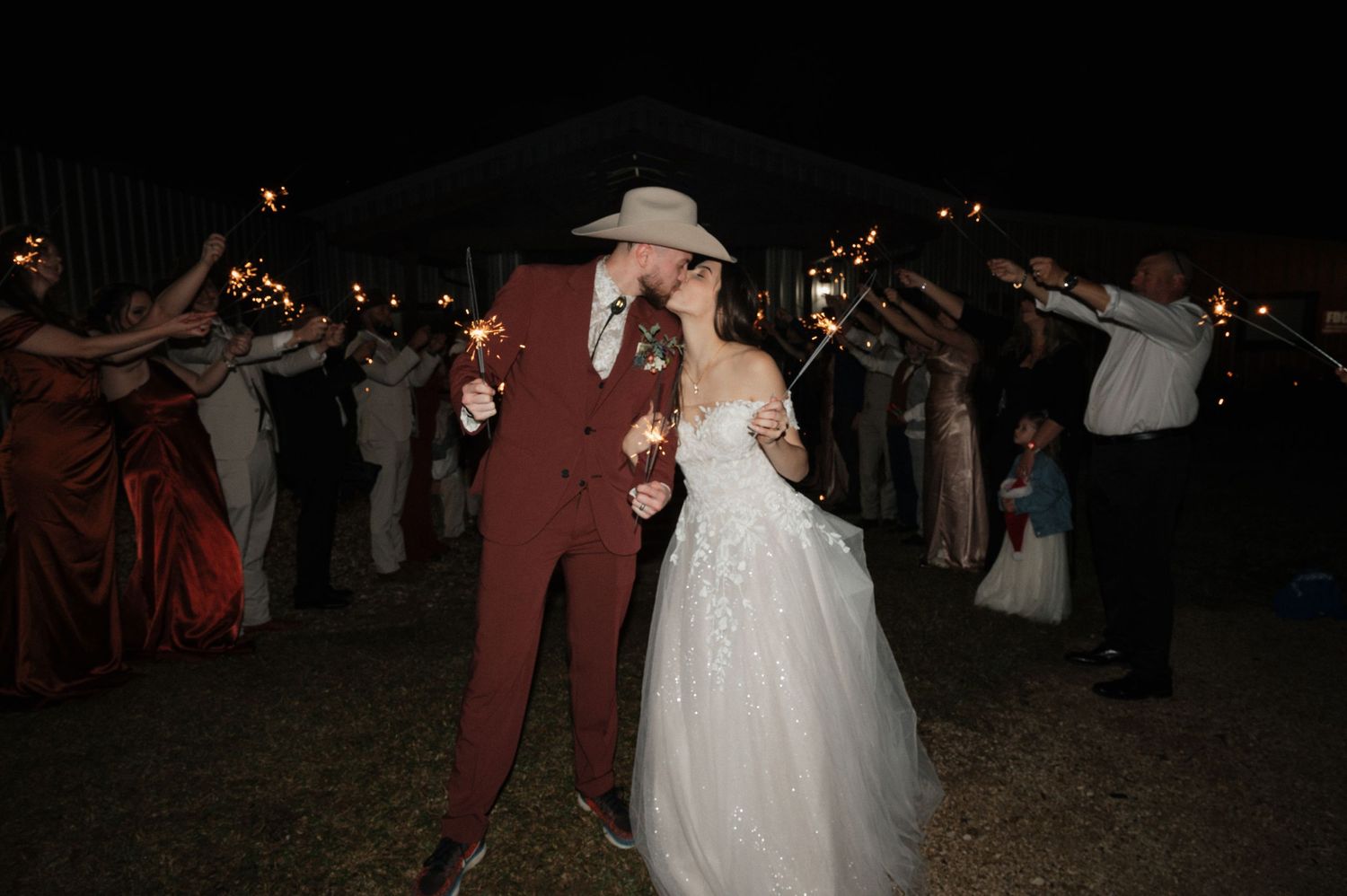 Couple dancing at nighttime outdoor wedding reception with guests forming circle around them.